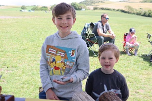 Two young boys smiling at the camera hold out fossils in their hands